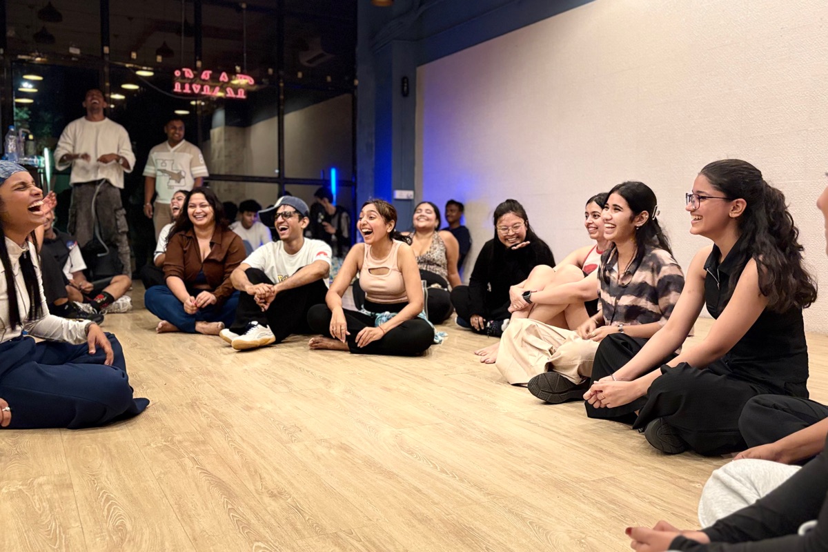 A class sitting in a circle on the studio floor, laughing