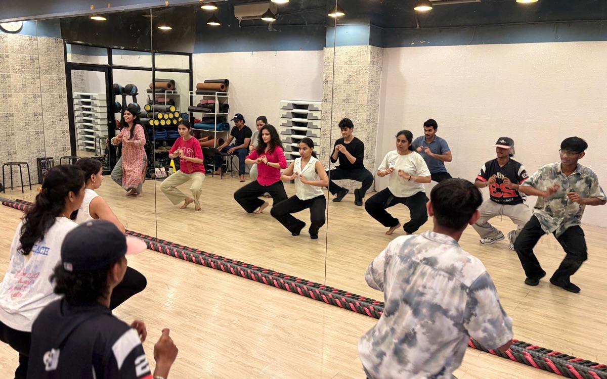 Dancers drilling a low squat in front of the studio mirror